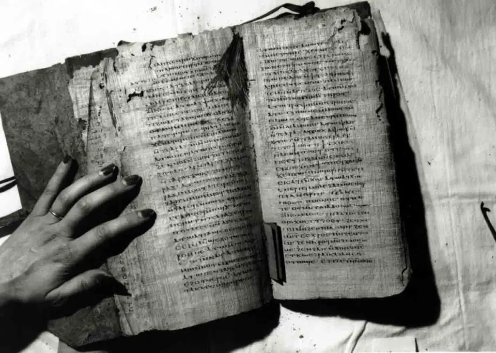 A hand holding open an ancient codex